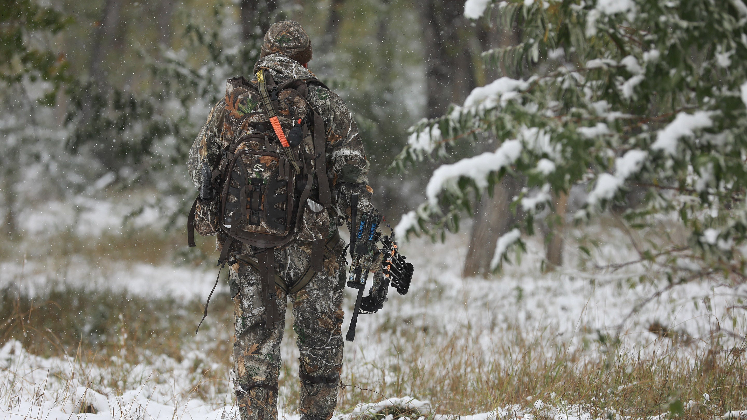 Deer hunter walking to treestand in camo clothing