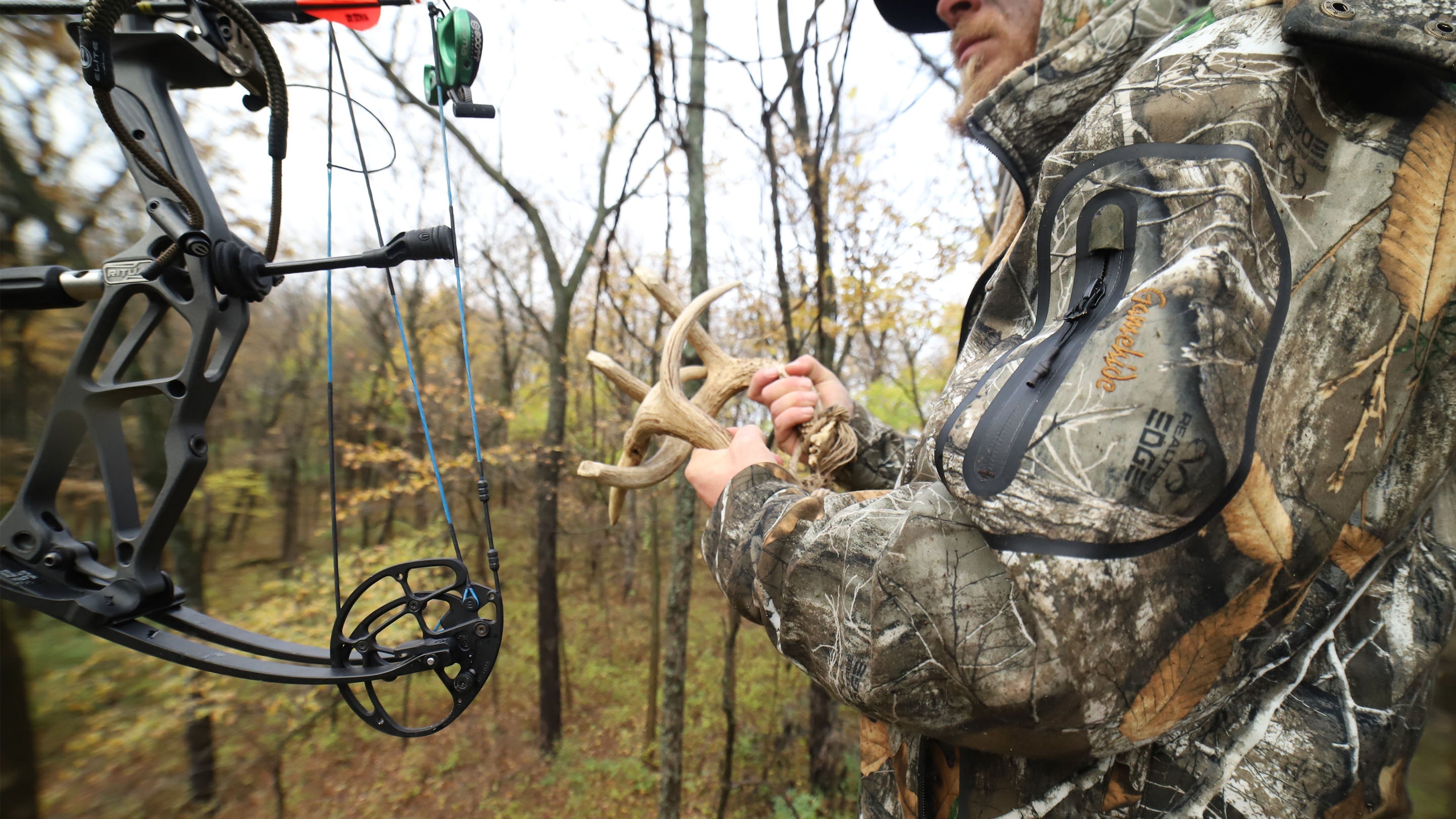 Bowhunter rattling antlers in treestand